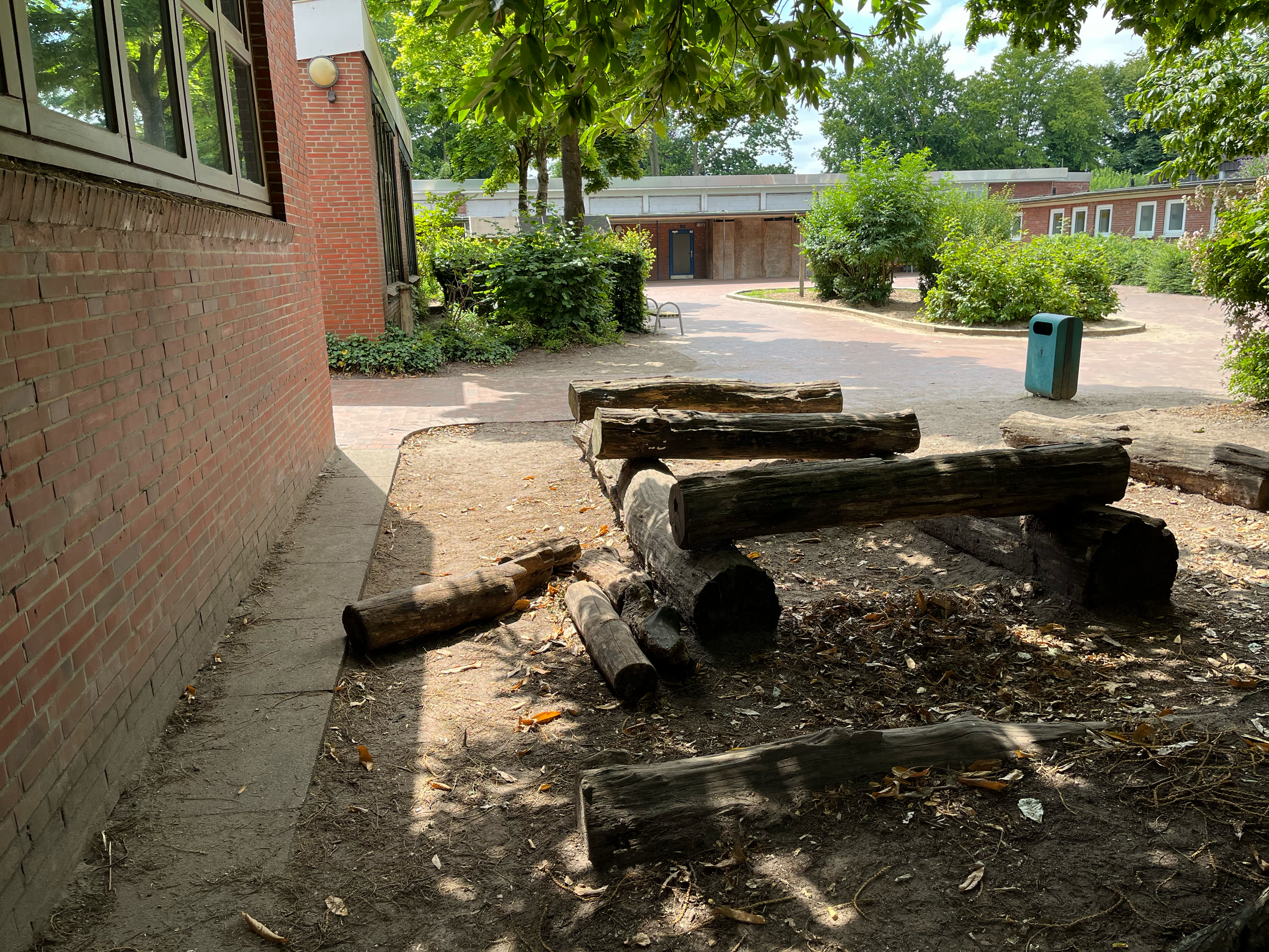 Baumstämme als Sitzgelegenheiten auf dem großen Schulhof
